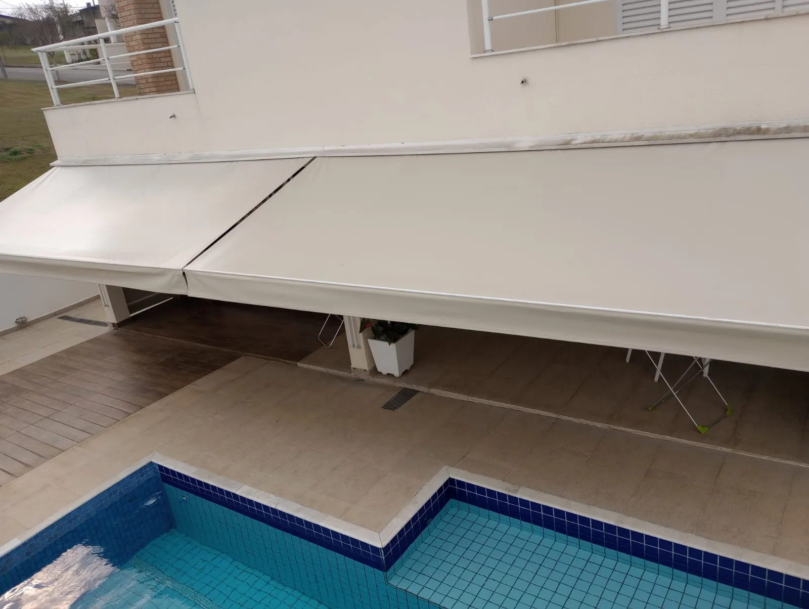 Toldo articulado aberto sobre área externa protegendo do sol